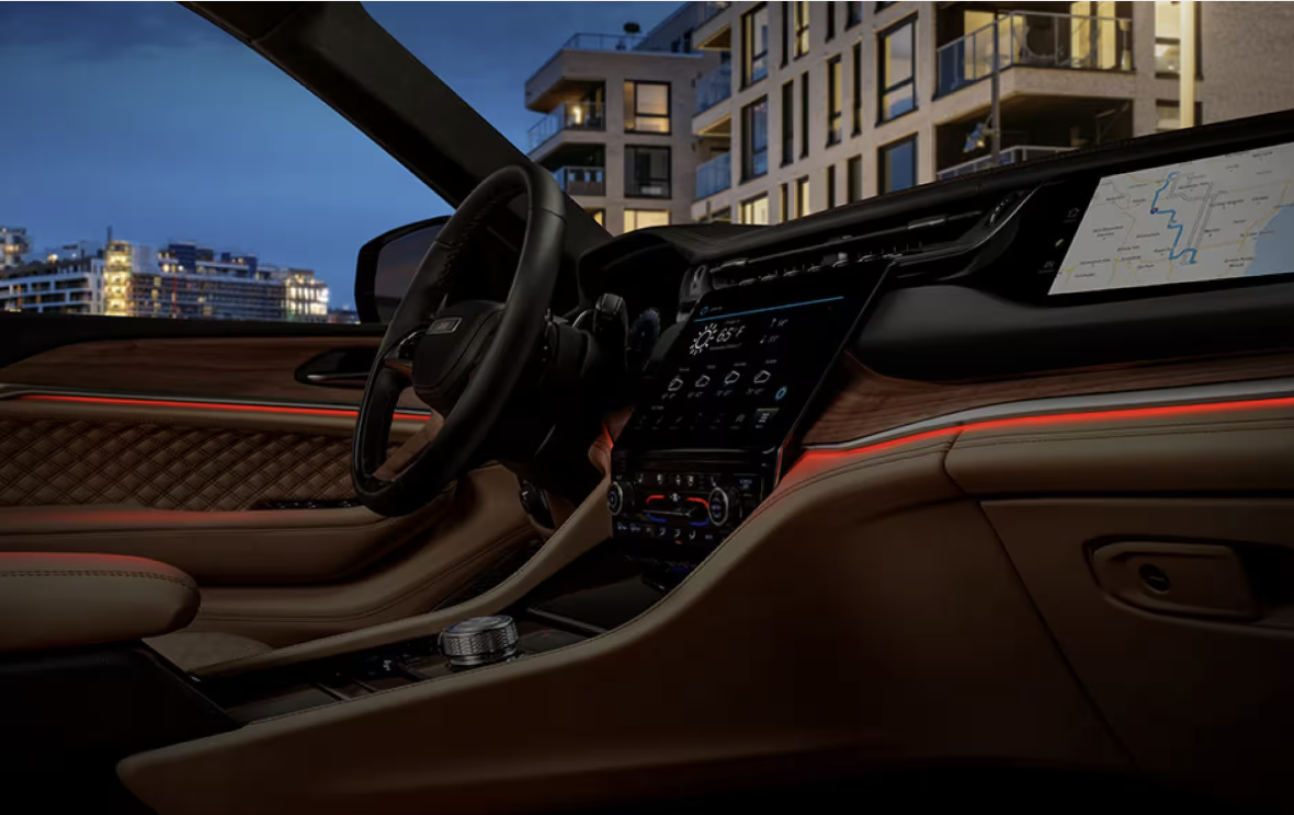 Jeep Grand Cherokee interior featuring dashboard, touchscreen display, and ambient lighting at night